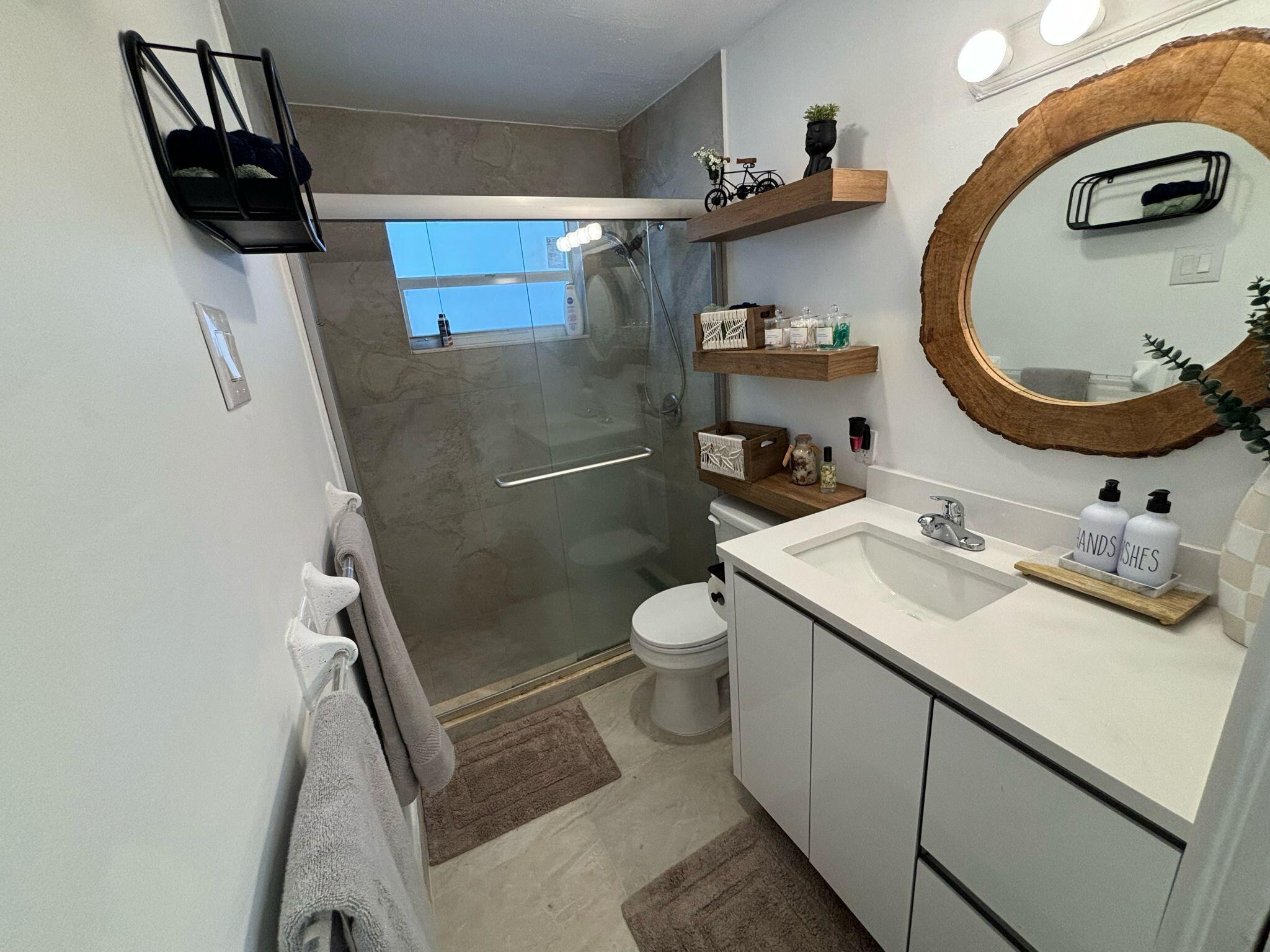 1150 East Sample Road Pompano Beach, FL 33064 - Photo 10 of 12 a bathroom with a sink a toilet and a mirror