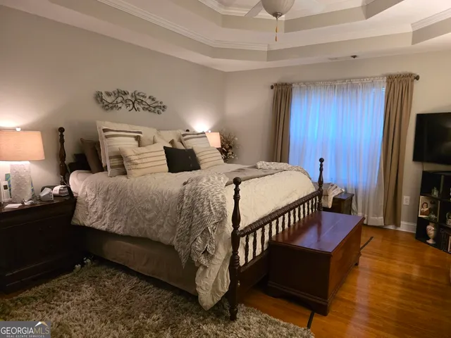 a bedroom with a bed a couch and a flat tv screen on dresser