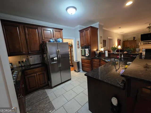 a kitchen with stainless steel appliances granite countertop a refrigerator a stove and a sink