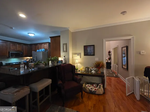 a living room with furniture kitchen view and a wooden floor