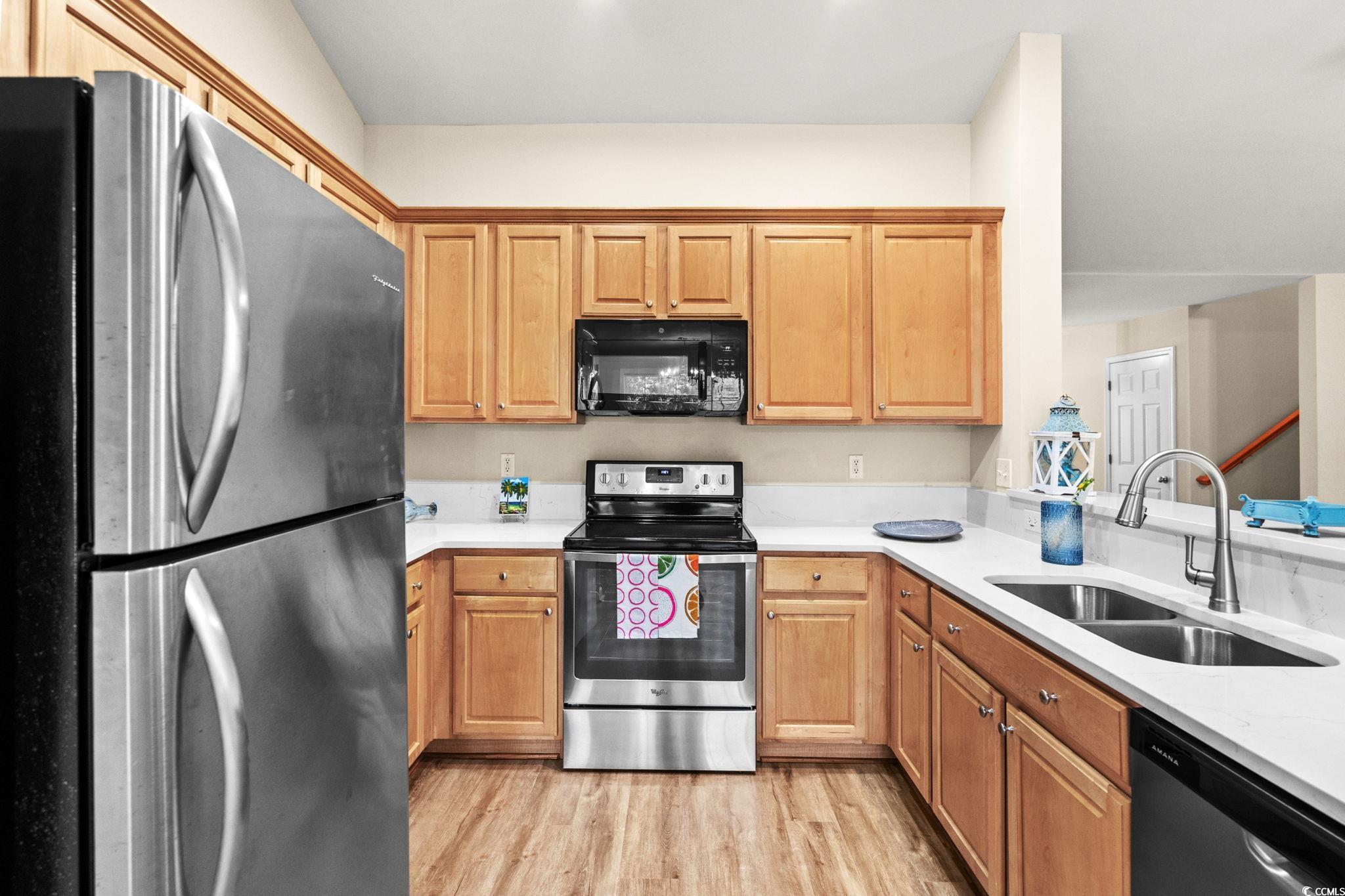 280 Barclay Drive Myrtle Beach, SC 29579 - Photo 16 of 38 Kitchen featuring appliances with stainless steel finishes, light wood-type flooring, light stone counters, and brown cabinets