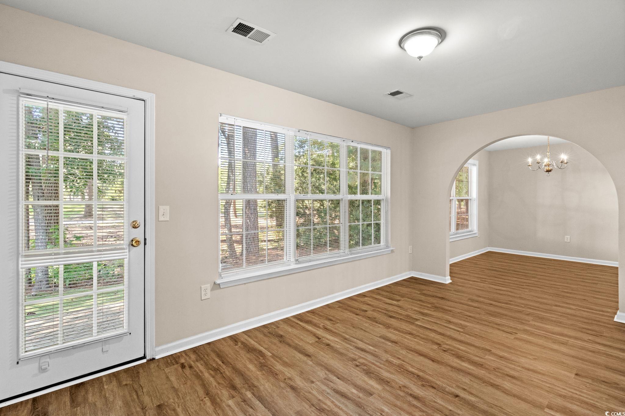 280 Barclay Drive Myrtle Beach, SC 29579 - Photo 22 of 38 Empty room featuring wood finished floors, a chandelier, and arched walkways