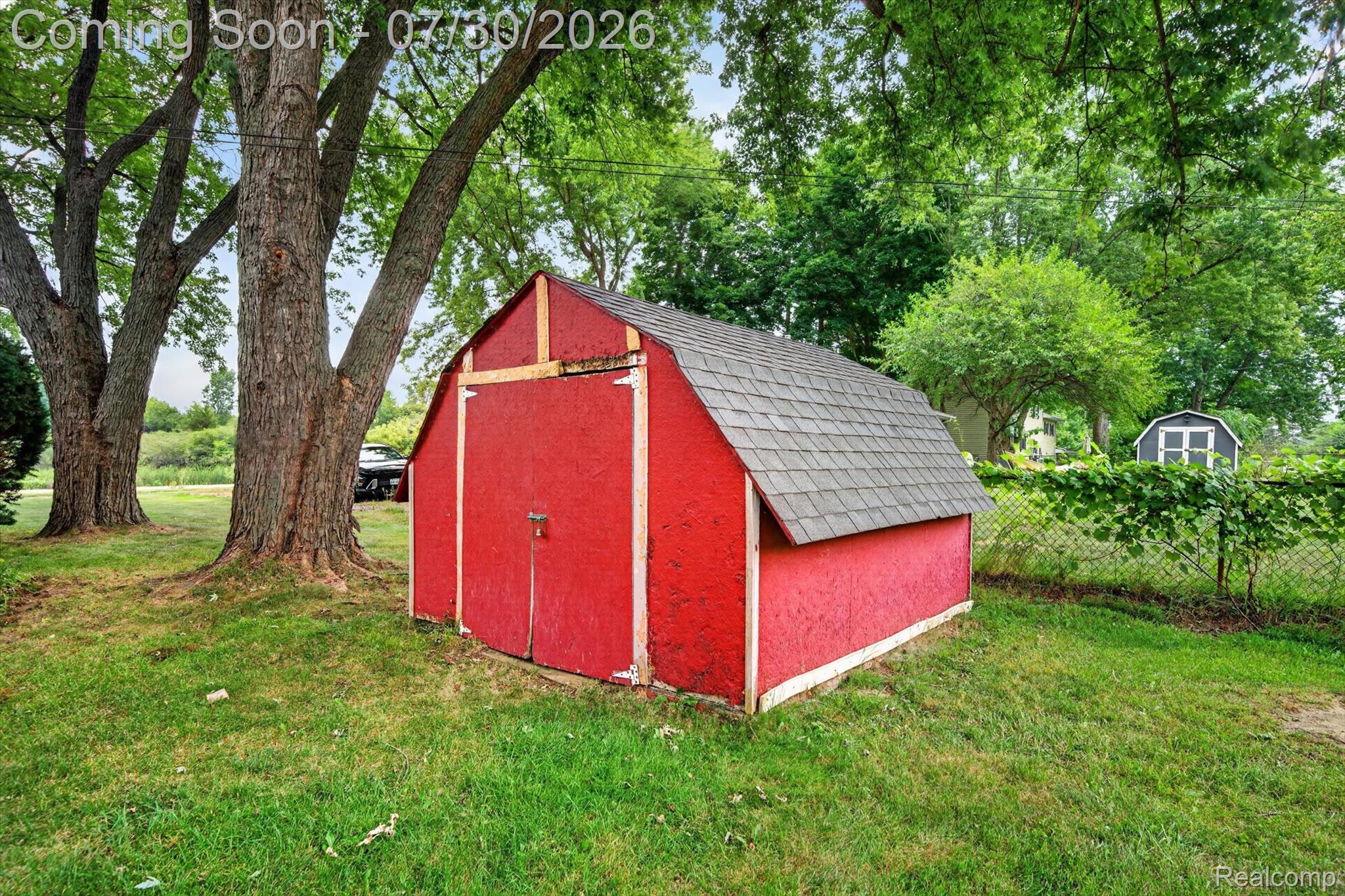 5991 Maybee Road Clarkston, MI 48346 - Photo 41 of 41 Red barn-style shed with shingle roof, double barn doors, and exterior lighting fixture