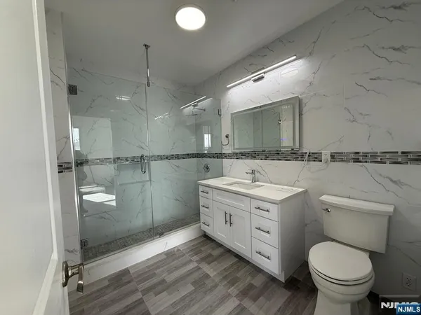 a bathroom with a granite countertop sink toilet and shower