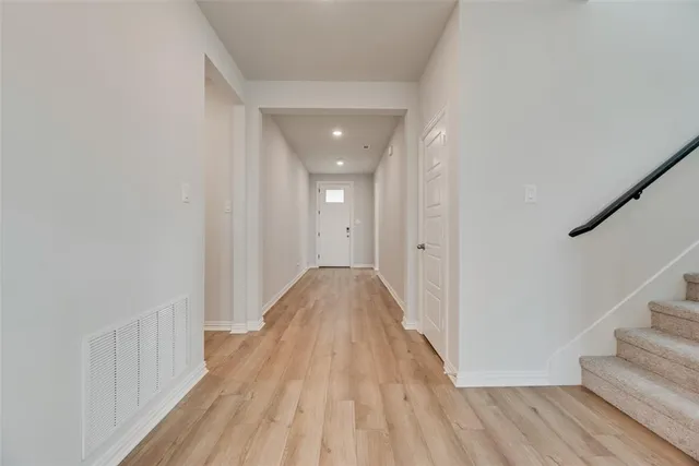 a view of a hallway with wooden floor and staircase