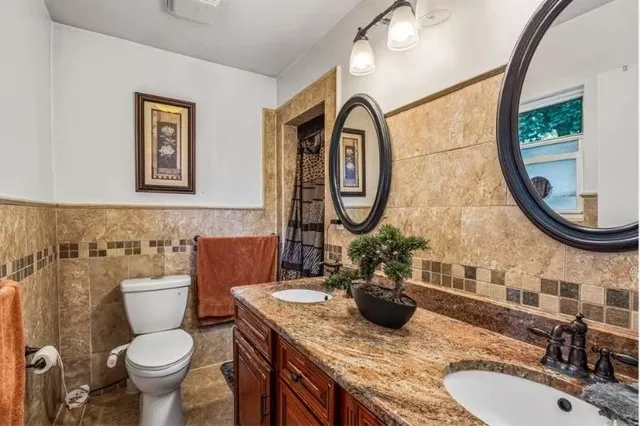 a bathroom with a granite countertop toilet a sink and a mirror