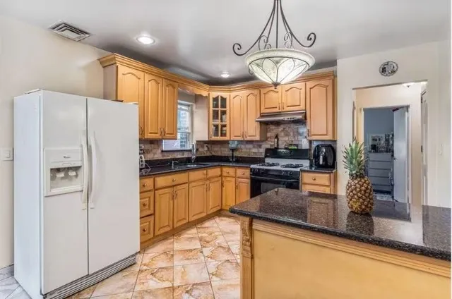 a kitchen with granite countertop a refrigerator a stove a sink and a granite counter tops