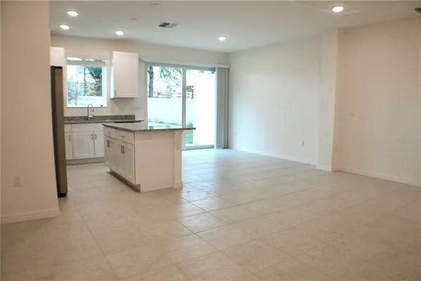 a large white kitchen with a sink a window and stainless steel appliances