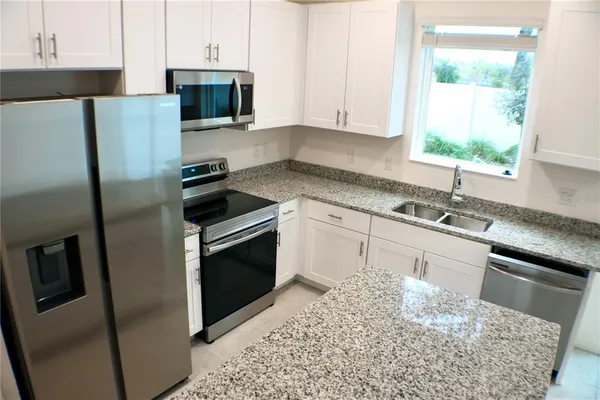a kitchen with stainless steel appliances kitchen island granite countertop a sink stove and refrigerator