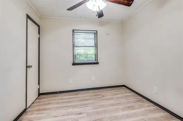 an empty room with a chandelier fan and windows