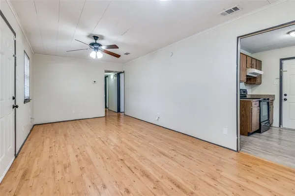 a view of empty room with wooden floor and ceiling fan
