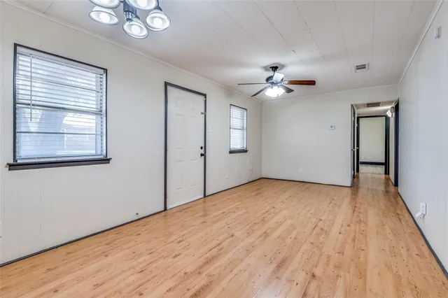 a view of empty room with wooden floor and fan