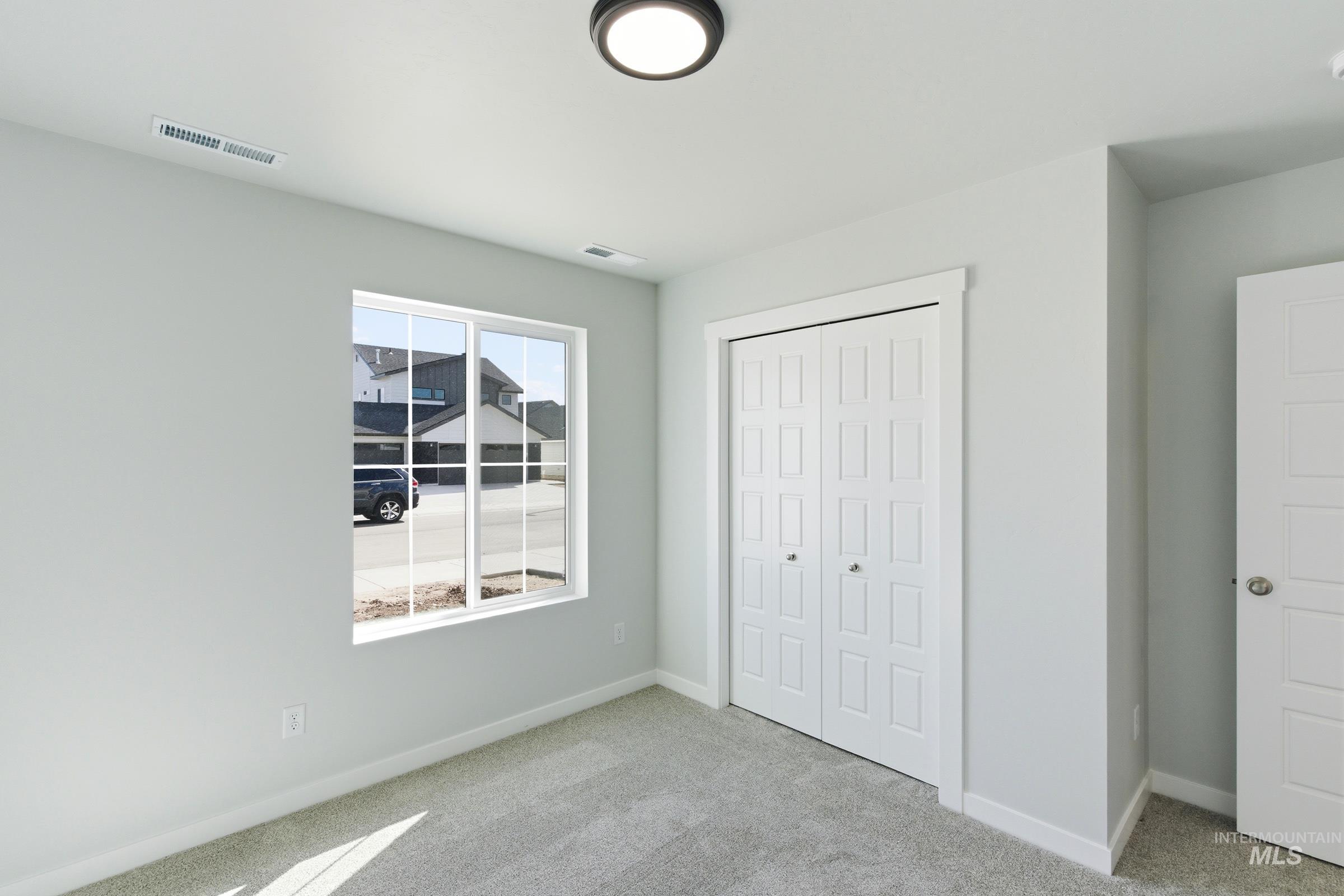 1059 West Jasper Street Meridian, ID 83642 - Photo 14 of 23 Carpeted interior space featuring a double-pane window with white grilles, white trim, a flush-mount ceiling light fixture, bi-fold closet doors, and light gray wall paint