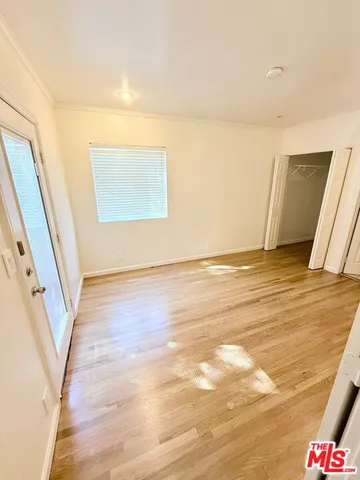 a view of an empty room with wooden floor and stairs