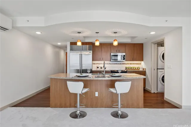 a kitchen with kitchen island granite countertop wooden cabinets and refrigerator