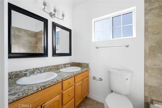 a bathroom with a granite countertop toilet sink and mirror