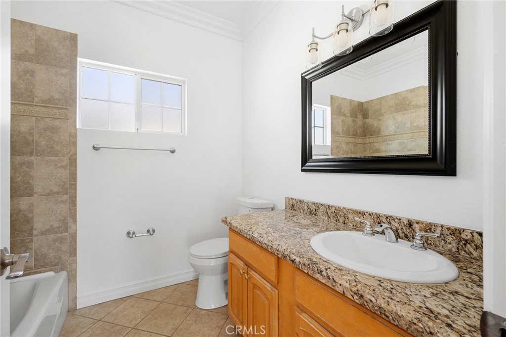 6831 Valmont Street, Unit 1 Tujunga, CA 91042 - Photo 22 of 30 a bathroom with a granite countertop sink toilet and mirror