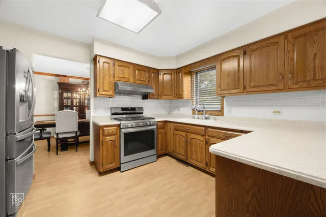 a kitchen with stainless steel appliances granite countertop a stove top oven a sink dishwasher and a refrigerator with wooden cabinets