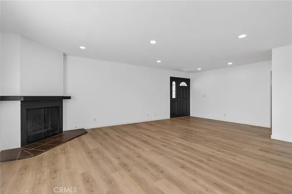 a view of an empty room with wooden floor and a fireplace