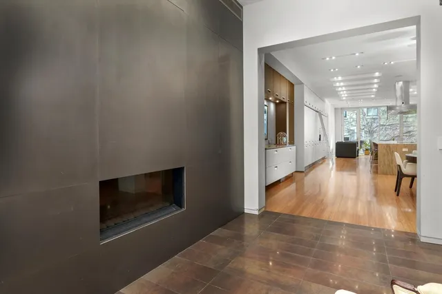 a living room with stainless steel appliances furniture a fireplace and wooden floor
