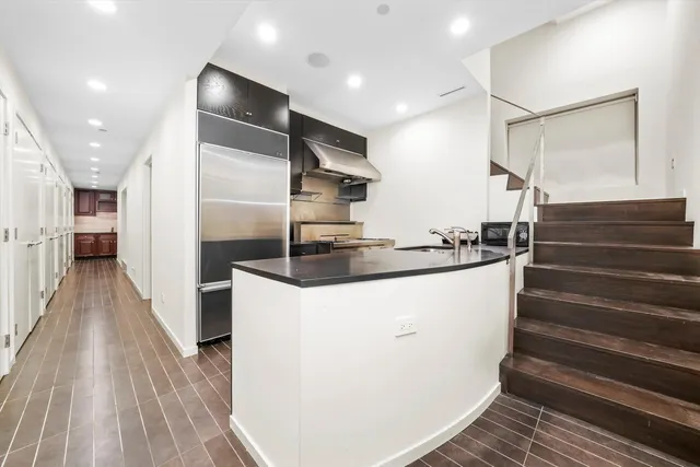 a kitchen with kitchen island a counter top space a sink wooden floor and entryway
