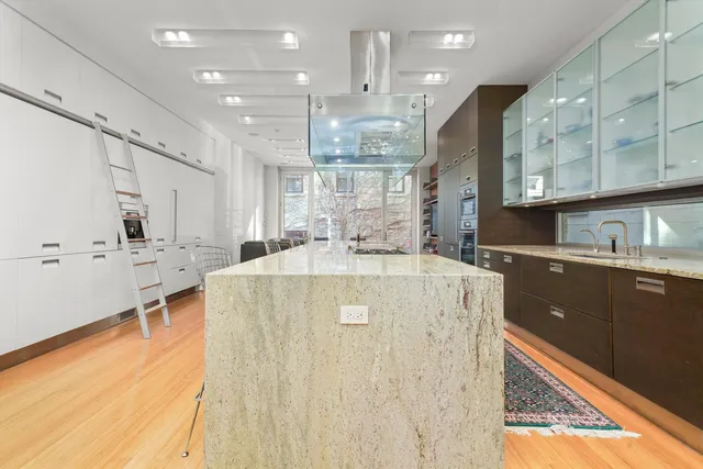 a large kitchen with a large counter top space a sink stainless steel appliances and cabinets