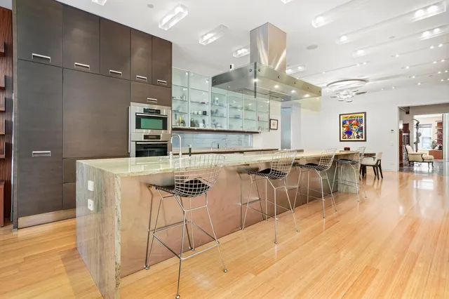 a kitchen with stainless steel appliances kitchen island granite countertop a table chairs and a refrigerator