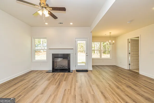 an empty room with wooden floor fireplace and windows
