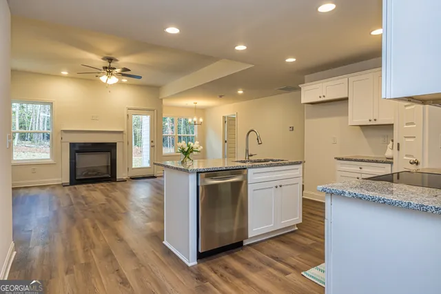 a kitchen with granite countertop a sink a stove a counter space and cabinets