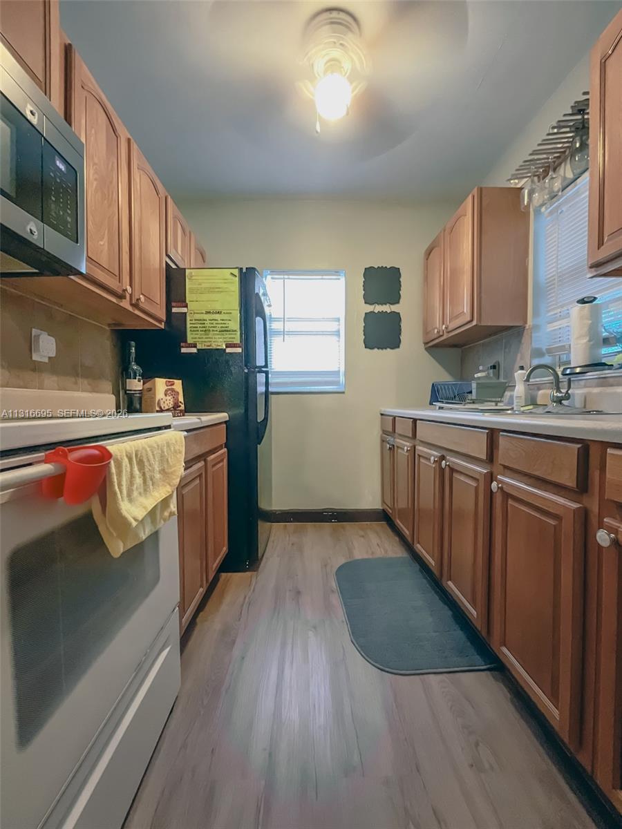 3682 Southwest 26th Street, Unit 2 Miami, FL 33133 - Photo 13 of 23 a kitchen with stainless steel appliances granite countertop a stove a sink dishwasher and a microwave oven with cabinets