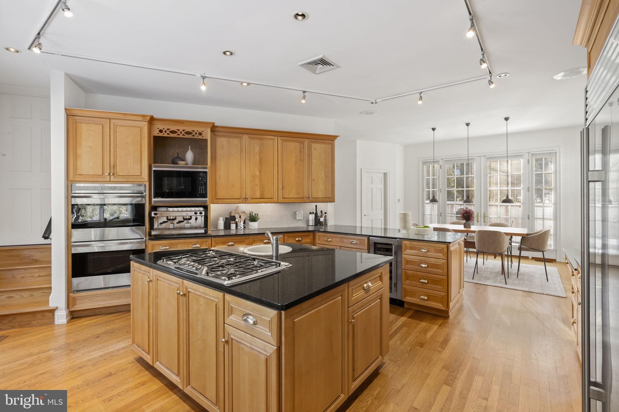 841 Mt Moro Road Villanova, PA 19085 - Photo 18 of 57 a kitchen with stainless steel appliances granite countertop a stove top oven a sink dishwasher a dining table and chairs with wooden floor