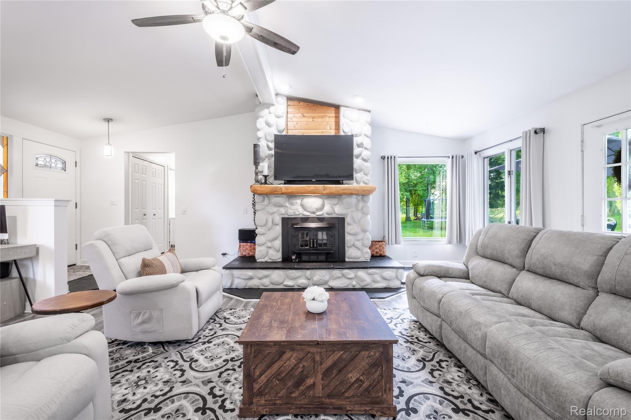 4418 North Gale Road Davison, MI 48423 - Photo 19 of 46 Living area featuring a stone-clad fireplace with a wood mantel, a ceiling fan with integrated lighting, and multiple windows