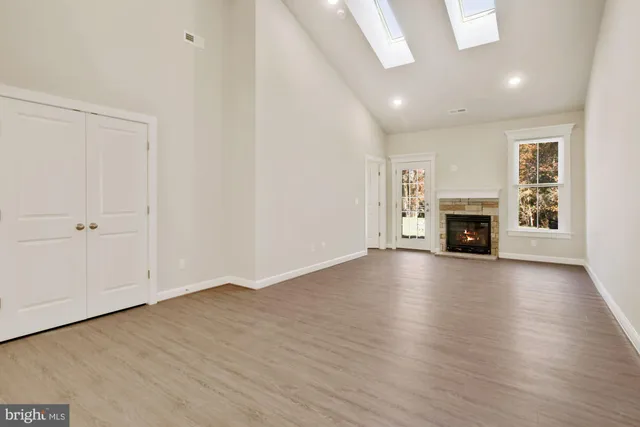 an empty room with wooden floor fireplace and windows