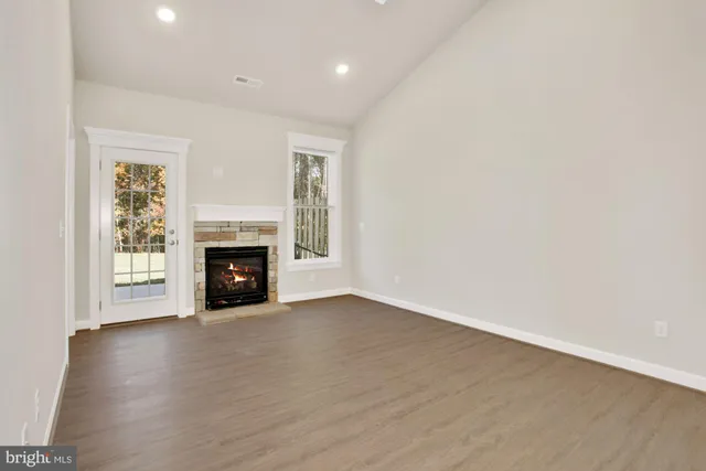 an empty room with wooden floor fireplace and windows