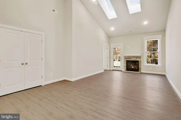 an empty room with wooden floor fireplace and windows