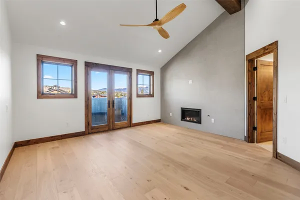 an empty room with wooden floor chandelier fan and windows