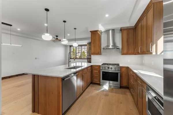 a kitchen with stainless steel appliances granite countertop a refrigerator a sink and wooden cabinets