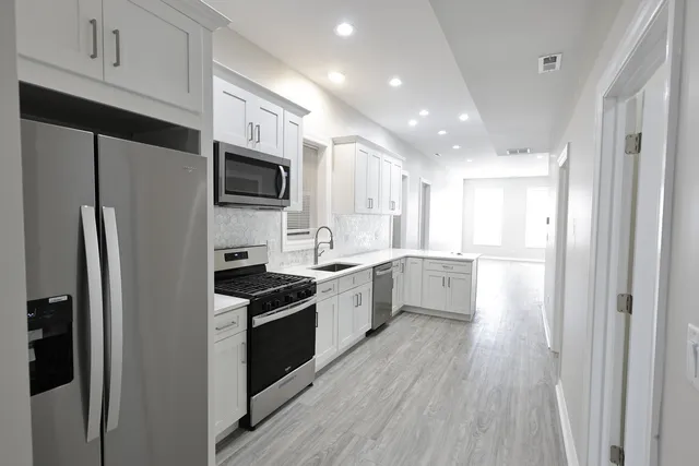 a large kitchen with a refrigerator a sink a stove top oven and cabinets