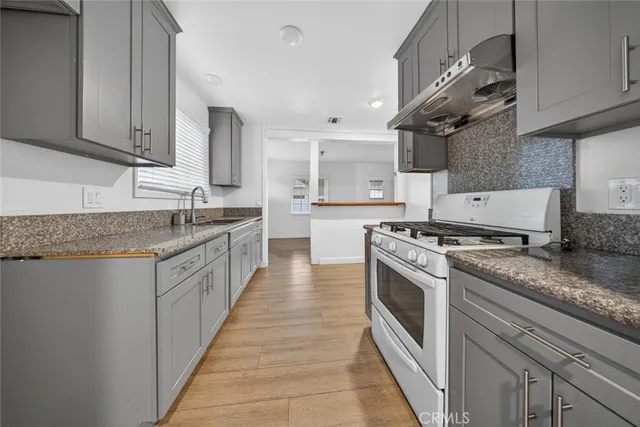 a large kitchen with stainless steel appliances granite countertop a stove a sink dishwasher and cabinets with wooden floor