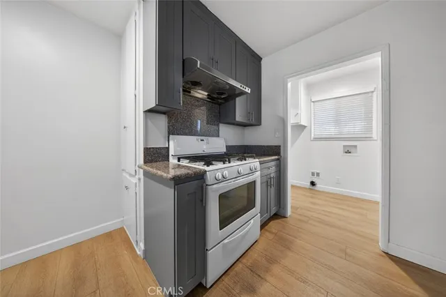 a kitchen with a stove and a wooden floor