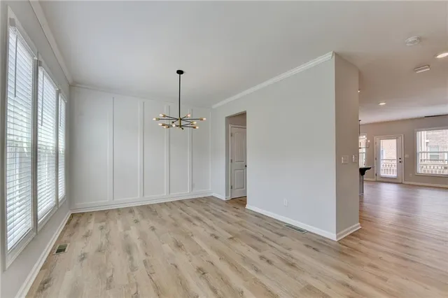 a view of a hallway with wooden floor and a chandelier