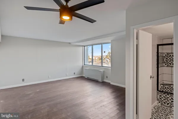 a view of an empty room with window and wooden floor