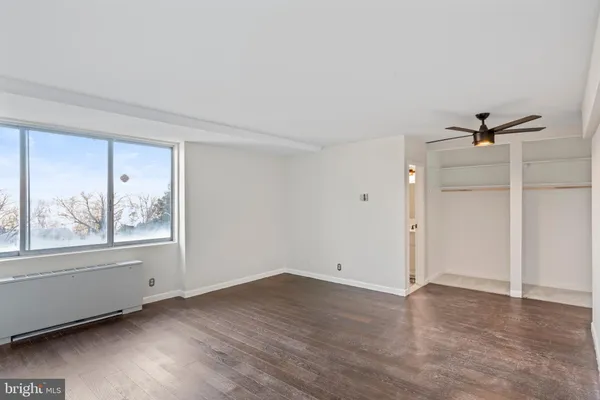 a view of an empty room with a window and wooden floor