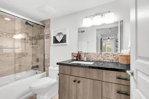 a bathroom with a granite countertop sink toilet a mirror a vanity and shower