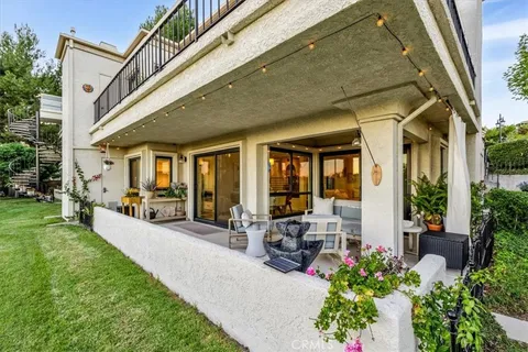 a view of a patio with table and chairs potted plants and floor to ceiling window and potted plants