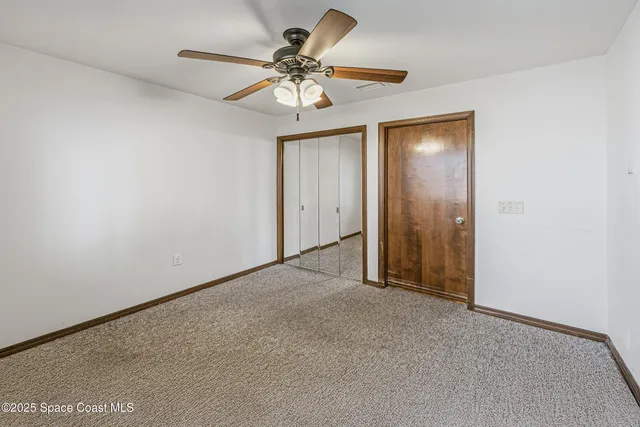 an empty room with chandelier fan and windows