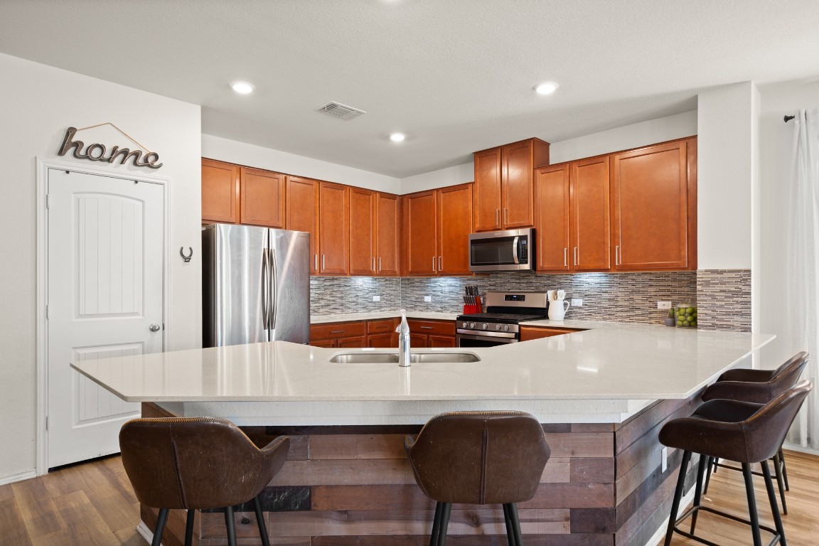 101 Kavanaugh Street Georgetown, TX 78628 - Photo 5 of 32 a kitchen with stainless steel appliances granite countertop a stove a refrigerator a sink a dining table and chairs with wooden floor