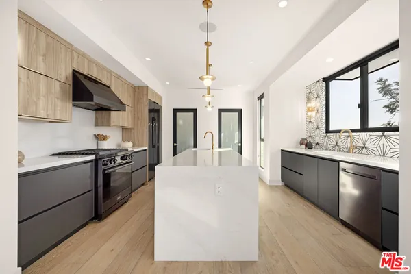 a large kitchen with stainless steel appliances granite countertop a stove a sink dishwasher and a refrigerator with white cabinets