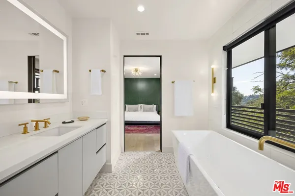 a en suite spacious bathroom with a tub mirror and window