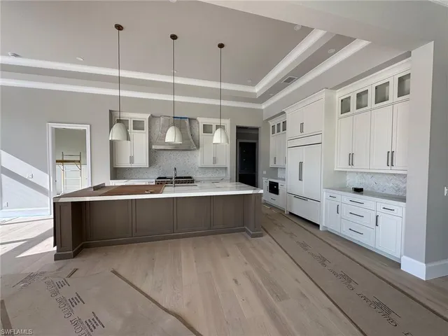 a large white kitchen with kitchen island a stove a sink dishwasher and wooden cabinets